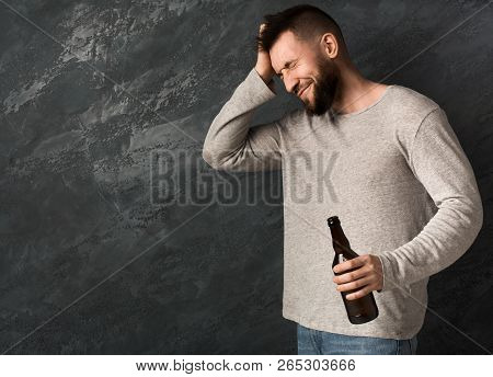 Man Suffering From Hangover With Beer Bottle, Alcohol Addiction And Consequences Concept, Copy Space