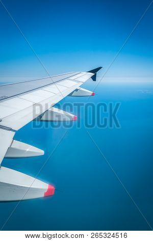 View From Airplane Window With Wing Flying Over Ocean On A Clear Day
