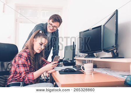 Image Of Happy Young Colleagues Sitting In Office, Working On Projekt And Using Desktop Computers