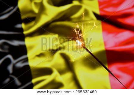 Close Up Of Sparkler Burning Over Belgia, Belgium Flag. Holidays, Celebration, Party Concept