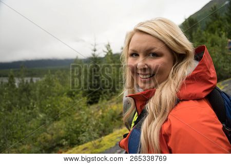 Female Hiker Wearing A Rain Jacket Enjoys The Views In Seward Alaska In The Wilderness Of Kenai Fjor