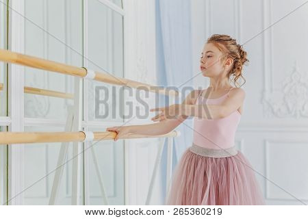 Young Classical Ballet Dancer Girl In Dance Class. Beautiful Graceful Ballerina Practice Ballet Posi