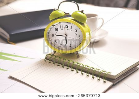 Clock On Notepad And Coffee On Desk