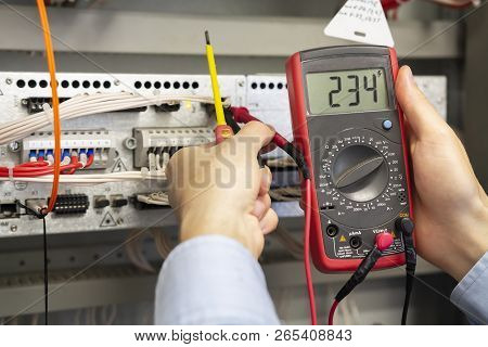 Electrician Measurements With Multimeter Tester. Male Technician Examining Fusebox With Multimeter P