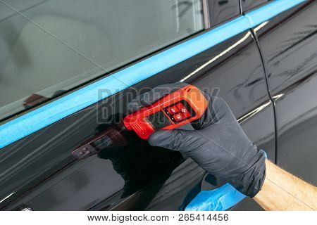 Male Hand Holds Device For Measuring Coating Thickness Before Polishing Car. Measuring Thickness Of 