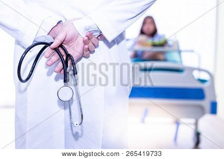 Handsome Doctor Hold Stethoscope Behind His Back. Attractive Handsome Doctor Guy Is Visiting His Pat