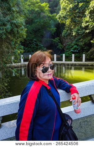 Senior women tourist stand beside the Lake on top of the xiqiao mountain foshan city china