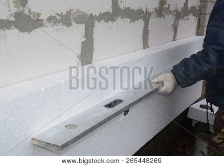 Builder Install Styrofoam Insulation Board And Measuring With Spirit Level. Exterior Foam Insulation