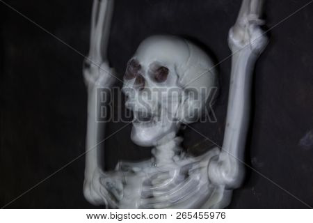Skeleton Hanging In The Darkness Ready To Scare People. Intentional Motion Blur To Convey Movement A