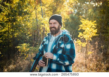 Hunter With Shotgun Gun On Hunt. Bearded Hunter Man Holding Gun And Walking In Forest