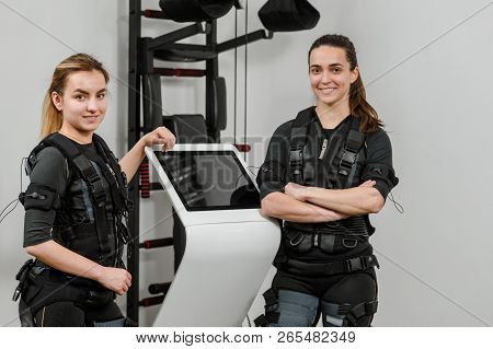 Happy Smiling Female Athletes Posing Near Ems Machine