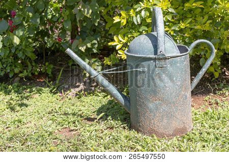 A Close Up View Of A Old Rusted Green Metal Water Can In The Outdoor Garden