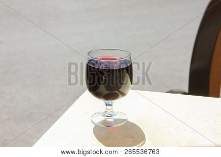 Glass Of Red Wine With A Beautiful Reflection And Shadow On White Table In Summer Cafe In Sunny Day