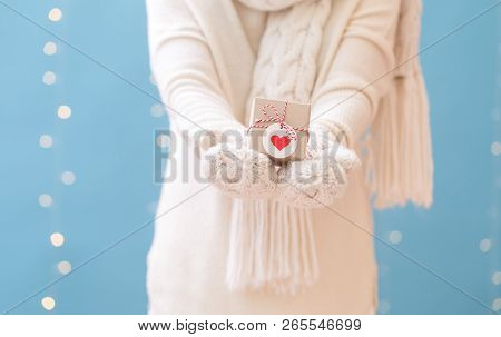 Woman Holding A Christmas Gift Box On A Shiny Light Blue Background
