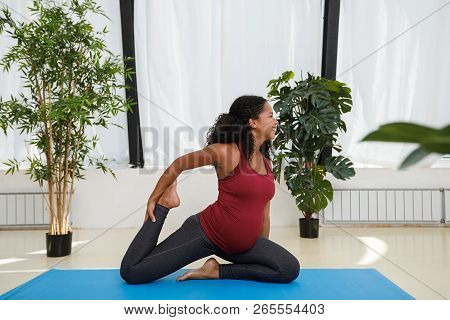 Pregnant Woman Doing Onelegged King Pigeon Pose In Studio