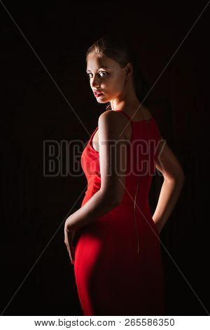 Seductive Look Of Aristocratic Lady In Red Long Dress Over Black Background