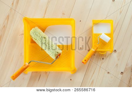 Paint Roller Brush At The Bucket With White Paint On Wooden Background