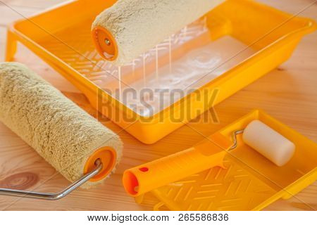 Paint Roller Brush At The Bucket With White Paint On Wooden Background