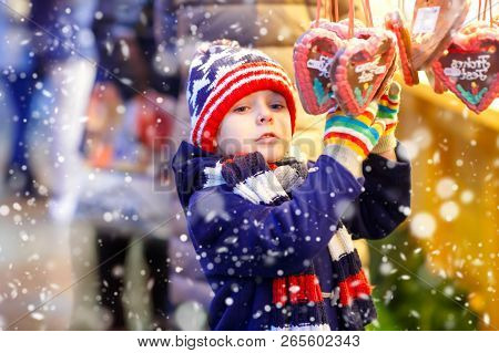 Little Cute Kid Boy Buying Sweets From A Cancy Stand On Christmas Market