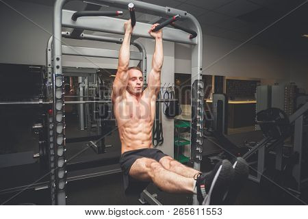 Fit Young Man Doing Leg Raises On A Pull Up Bar