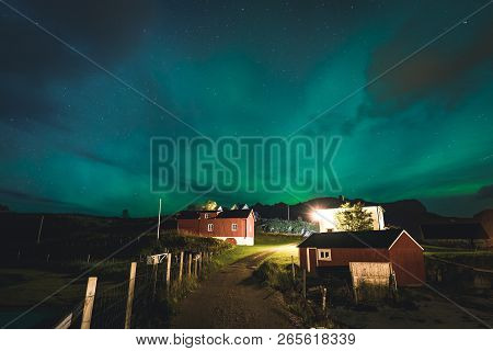 Aurora Over Traditional Red Fisher House In Norway, Lofoten Islands. Northern Lights In Lofoten Isla