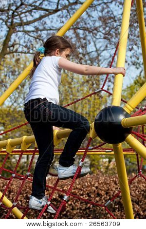 Mädchen Klettern einen gelben Rahmen auf einem Spielplatz