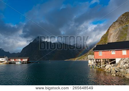 Rainbow Ofer Red Houses Rorbuer Of Reine In Lofoten, Norway With Red Rorbu Houses, Clouds, Rainy Blu