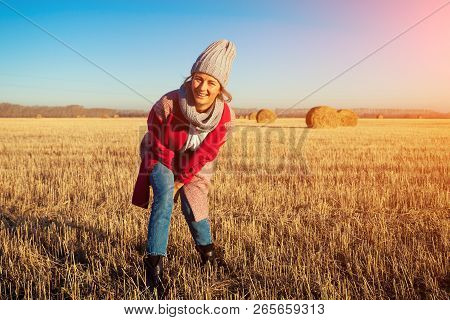 Young Attractive Lady In Gray Knitting Hat And Pink Coat Posing Around Haystick. Smiling Beautiful H