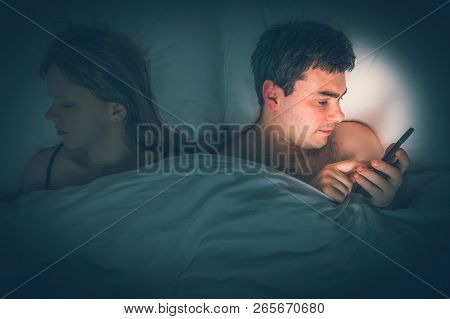 Young Man Using Mobile Phone, While His Wife Sleep At Night - Insomnia And Cheating Concept - Retro 