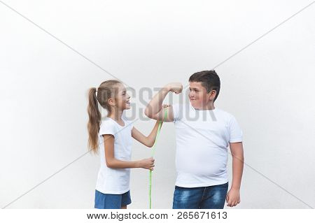 Healthy Slim Little Girl Tease Big Fat Boy Measuring His Muscle With Tape Copyspace