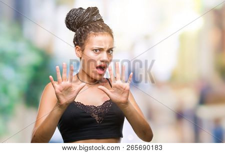 Young braided hair african american with pigmentation blemish birth mark over isolated background afraid and terrified with fear expression stop gesture with hands, shouting in shock. Panic concept.
