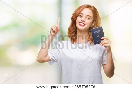 Young beautiful woman holding passport of germany over isolated background surprised with an idea or question pointing finger with happy face, number one
