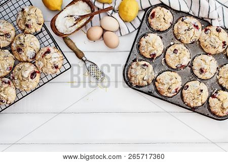 Cranberry Muffins In A Muffin Tin With Fresh Eggs, Sugar, Lemons And Lemon Zest Over A Rustic White 