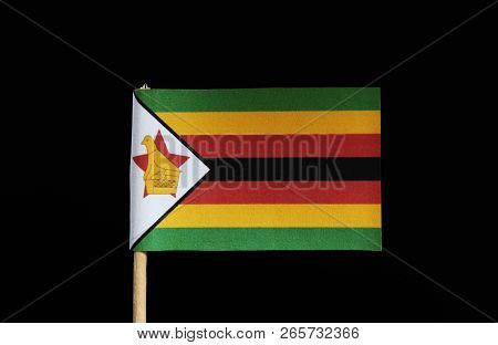 A National Flag Of Zimbabwe On Toothpick On Black Background. Flag Contain Five Colours. Red, Black,