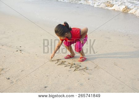 Little Girl Writing On Wet Sand At Alibag Beach, India