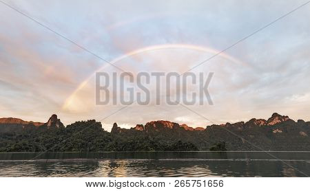 Mountain Nature And Lake Background With Bright Rainbow In Dramatic Cloudy Sky