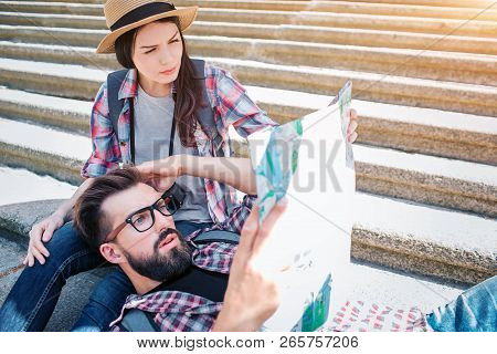 Picture Of Serious Tourists On Steps. He Is Lying On Girlfriends Knees And Hold Map In Hanad. She Si