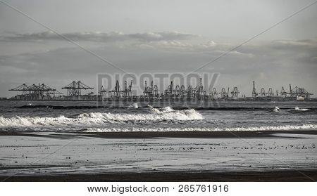 Commercial Port Cranes In The Horizon And Beach