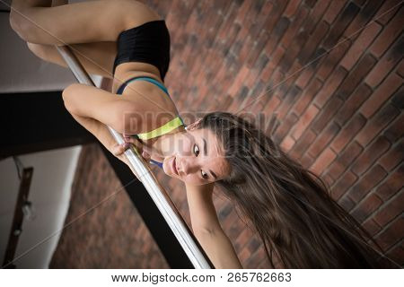 Girl Training Pole Dance Hanging Upside Down In A Studio.