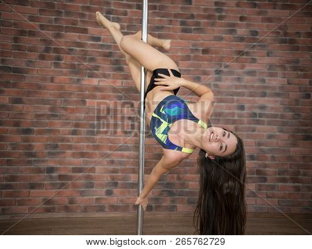 Girl Training Pole Dance Hanging Upside Down And Smiling In A Studio