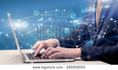 Businessman typing on laptop with linked reports charts grapghs around
