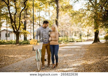 Active Young Couple Enjoying Romantic Walk With Bicycle In Golden Autumn Park
