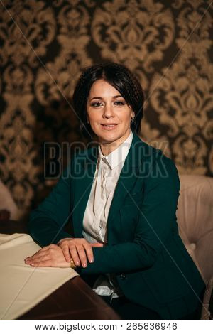 Woman Sist On Chair In Restaurant In Green Jaket