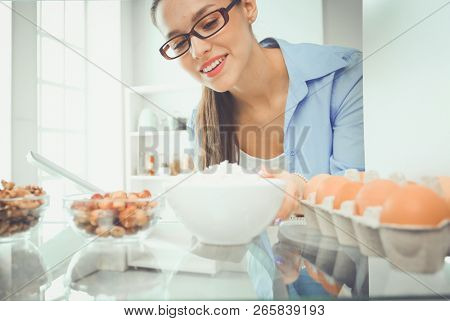 Portrait of female standing near open fridge full of healthy food, vegetables and fruits. Portrait of female