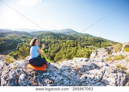 A Woman Is Sitting In A Sleeping Bag At Sunset. Camping On Top Of A Mountain. A Smiling Girl Rests A
