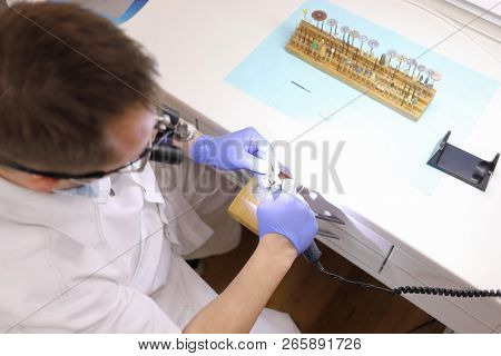 MOSCOW - JAN 10, 2018: Chief of clinic with portable microscope works with denture in Razumenko dental clinic