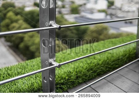 Details Of Fence Made Of Stainless Steel Profile With An Artificial Raffa On The Background.