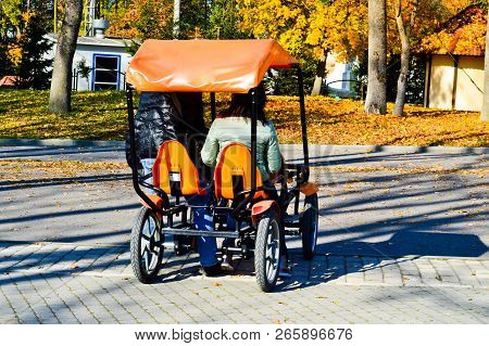 People Ride A Trendy Orange Four-wheeled Bicycle, A Cycle Card With A Wheel In The Autumn Park.