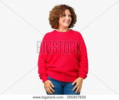 Beautiful middle ager senior woman red winter sweater over isolated background looking away to side with smile on face, natural expression. Laughing confident.