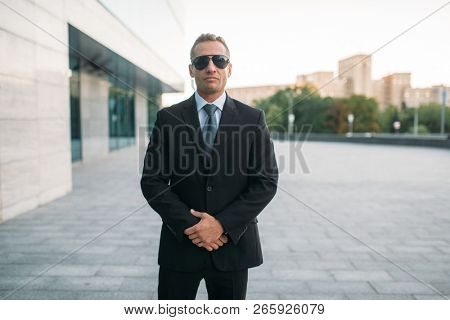 Male bodyguard in suit, earpiece and sunglasses